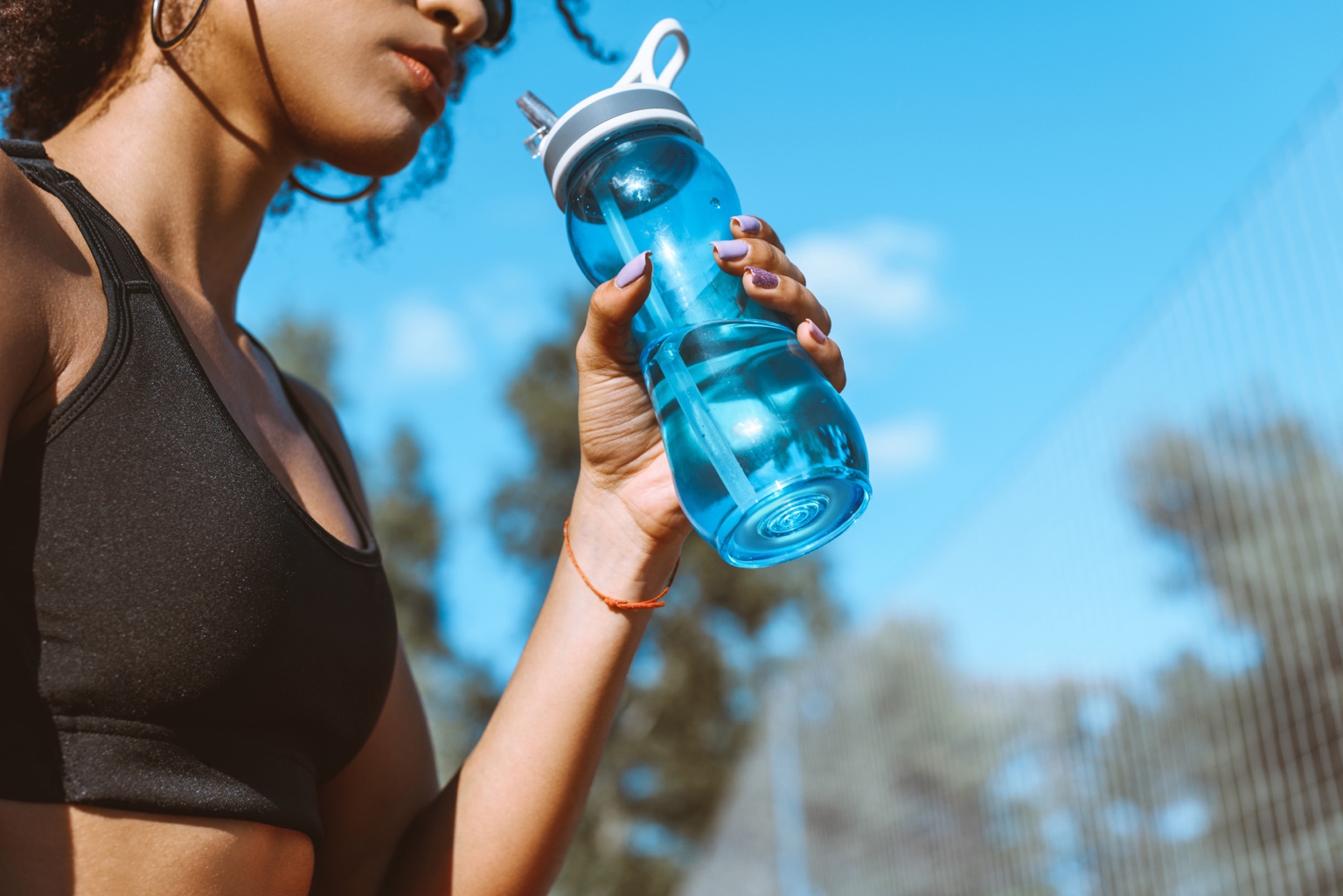 Woman outdoors holding a blue reusable water bottle